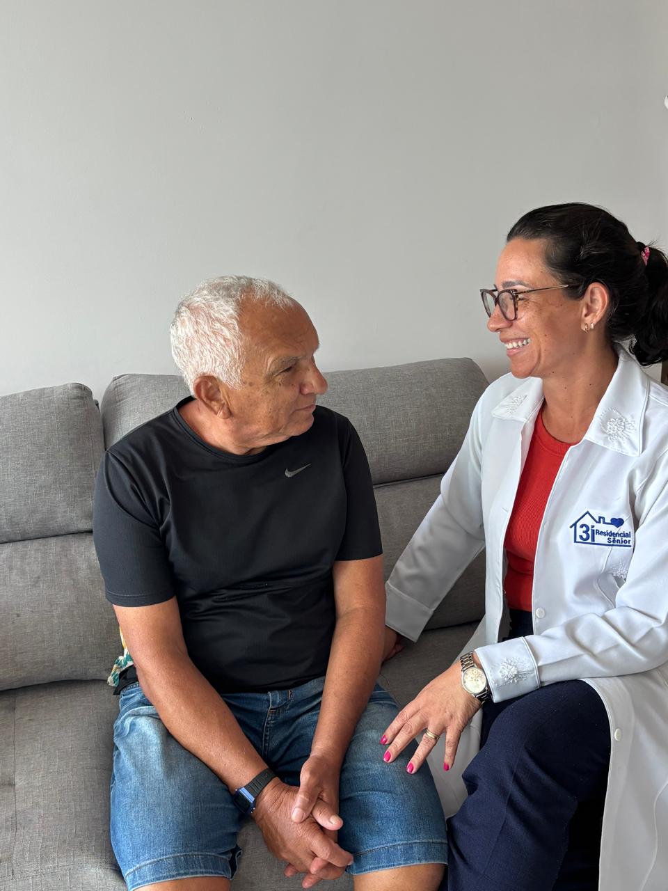 Profissional da 3i conversando com idoso na sala de casa, em Recife
